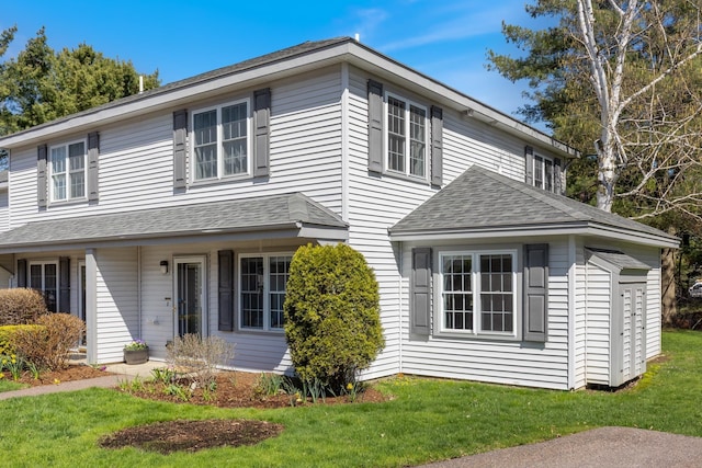 view of front facade featuring a shingled roof and a front lawn