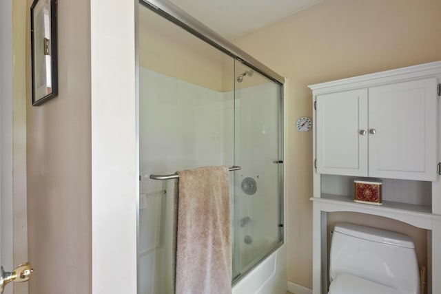 bathroom featuring enclosed tub / shower combo and toilet