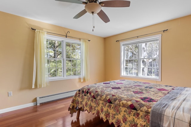 bedroom featuring ceiling fan, baseboards, a baseboard radiator, and wood finished floors