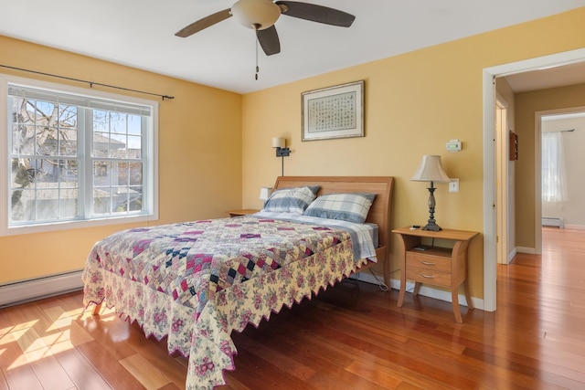 bedroom with baseboards, ceiling fan, baseboard heating, and wood finished floors
