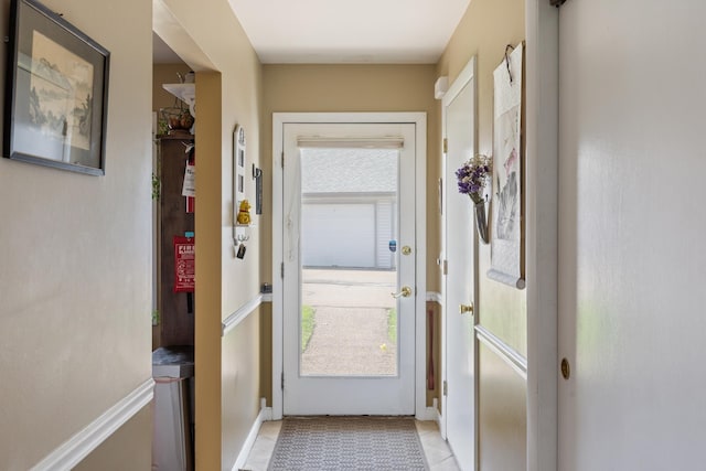 doorway with light tile patterned flooring and baseboards