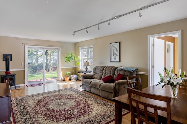 living room featuring a wood stove, rail lighting, and wood finished floors
