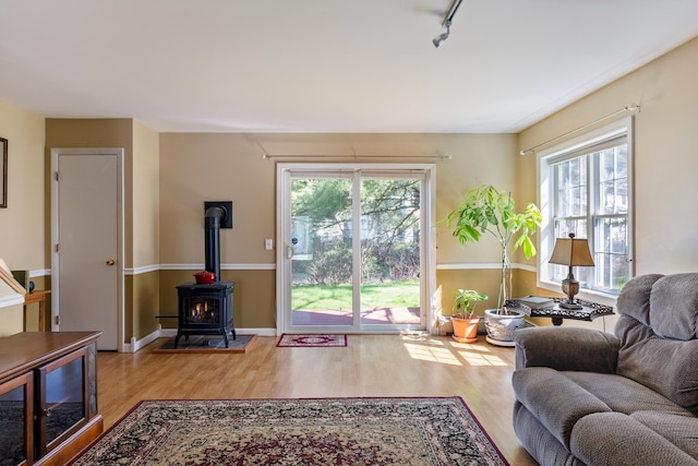 living area with track lighting, a wood stove, baseboards, and wood finished floors