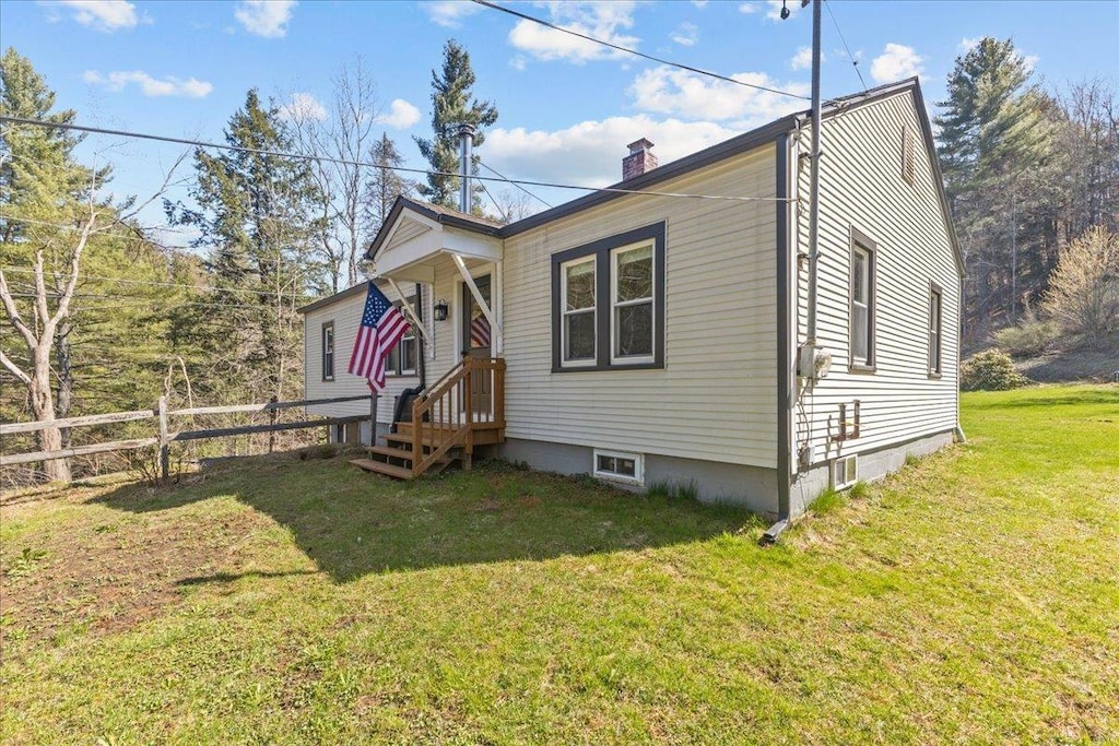 bungalow featuring fence, a chimney, and a front lawn