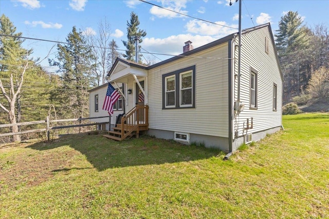 bungalow featuring fence, a chimney, and a front lawn