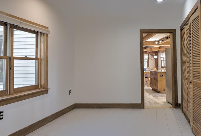 spare room with baseboards and beamed ceiling