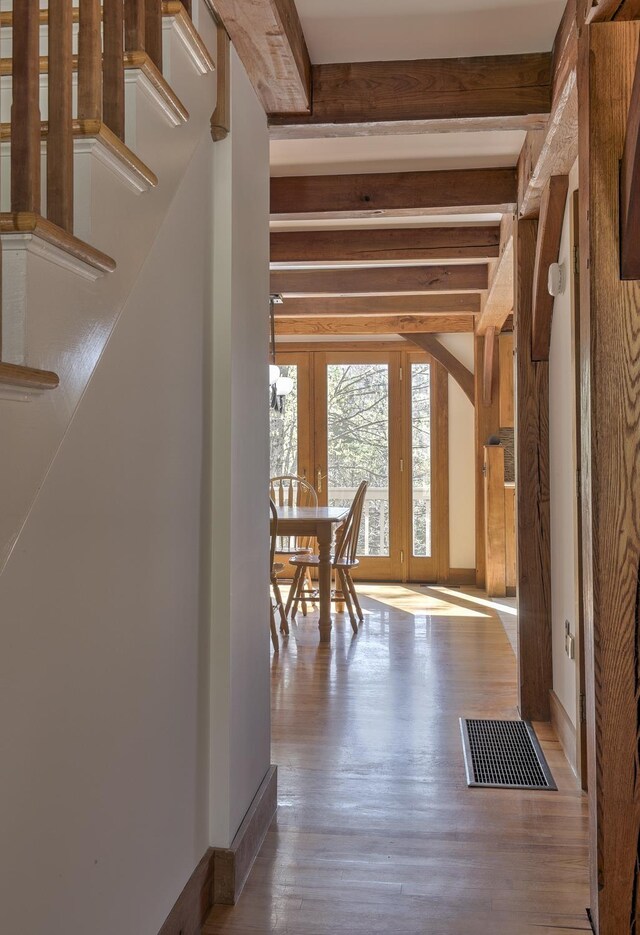 interior space with visible vents, wood finished floors, french doors, and beamed ceiling