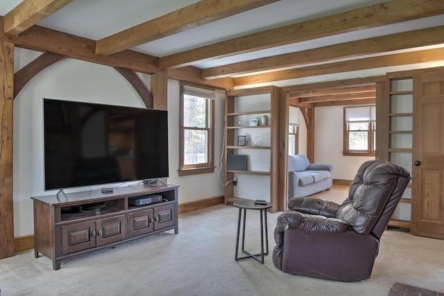 living area with baseboards, beam ceiling, and light colored carpet