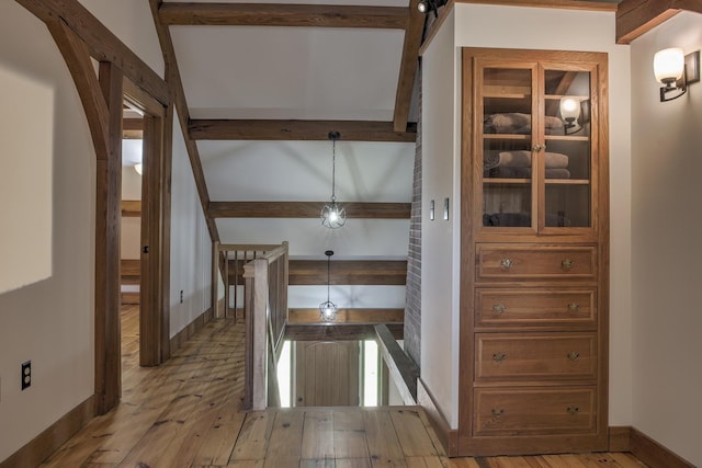 hallway with beamed ceiling, baseboards, and hardwood / wood-style floors