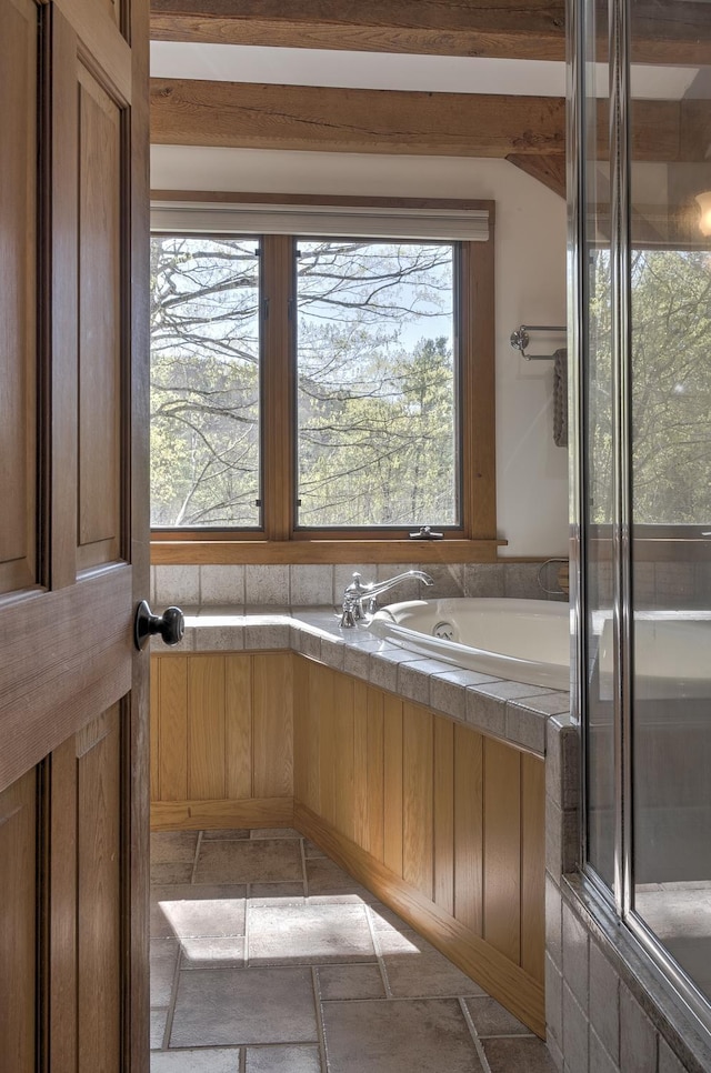bathroom featuring an enclosed shower, a bathtub, and stone tile flooring