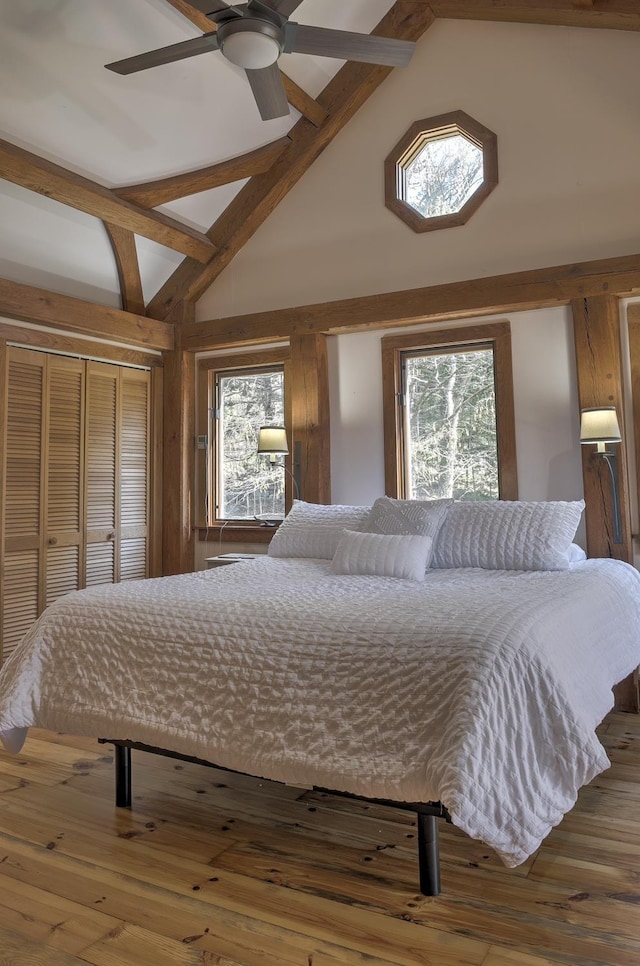 bedroom with high vaulted ceiling, multiple windows, and hardwood / wood-style flooring