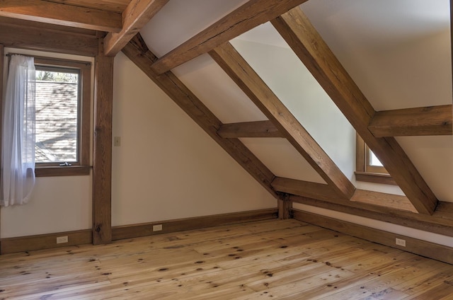 additional living space with light wood-style floors, baseboards, and vaulted ceiling with beams