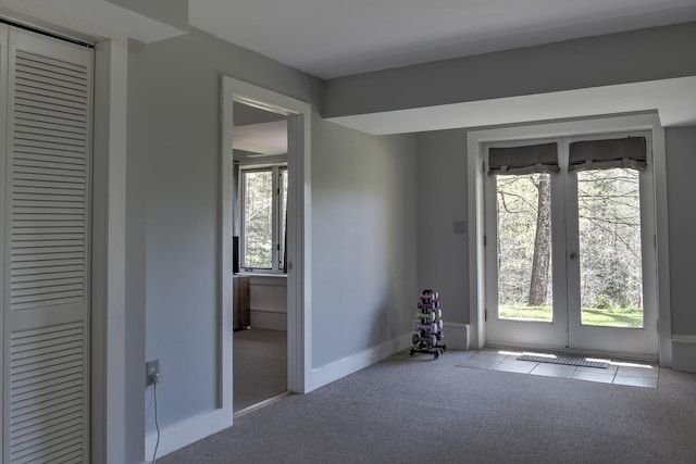 spare room with carpet floors, plenty of natural light, baseboards, and french doors