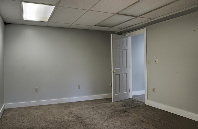 carpeted empty room featuring baseboards and a drop ceiling
