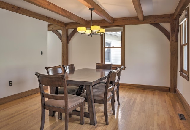 dining space featuring baseboards, light wood finished floors, and a chandelier