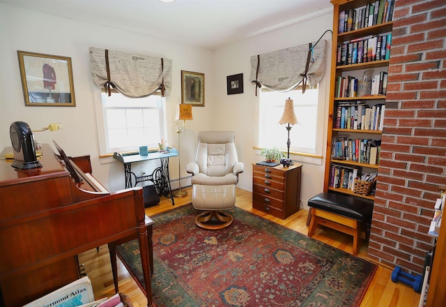 sitting room featuring wood-type flooring, a desk, and a baseboard heating unit