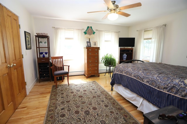 bedroom with light wood finished floors, baseboard heating, and a ceiling fan
