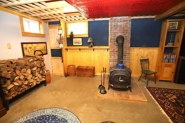 below grade area featuring a wood stove, wood walls, and wainscoting