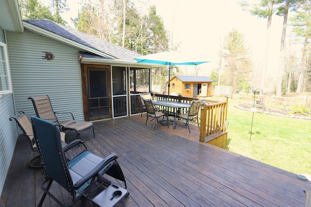 deck with outdoor dining space, an outdoor structure, and a sunroom