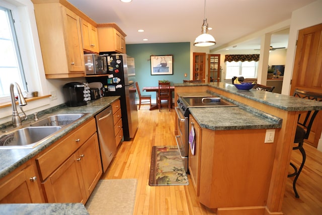 kitchen featuring a sink, stainless steel appliances, recessed lighting, dark countertops, and light wood-style flooring