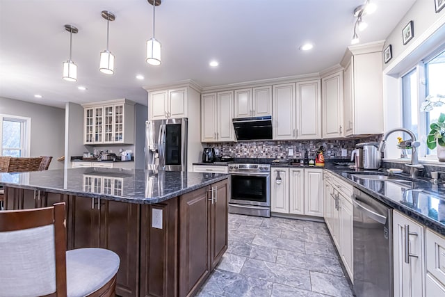 kitchen with plenty of natural light, a sink, appliances with stainless steel finishes, and a kitchen bar