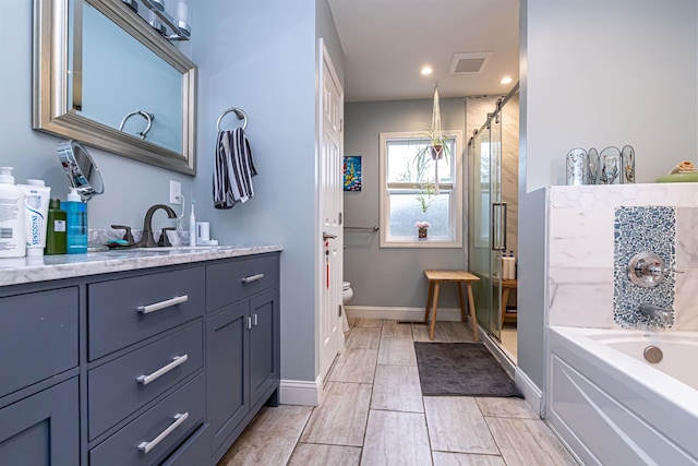 bathroom featuring vanity, toilet, visible vents, a bath, and a stall shower