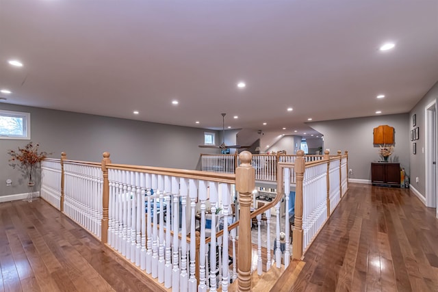 hallway with baseboards, wood-type flooring, recessed lighting, and an upstairs landing
