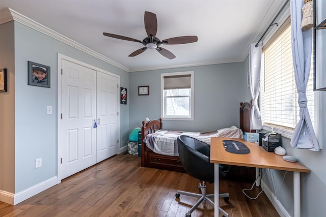 bedroom with a closet, ornamental molding, baseboards, hardwood / wood-style flooring, and a ceiling fan