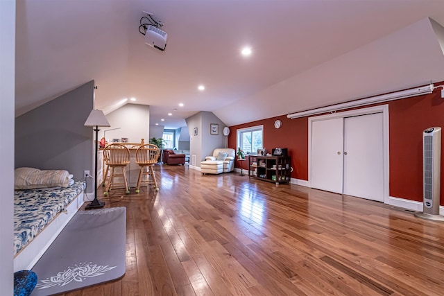 bedroom featuring baseboards, a heating unit, wood finished floors, and vaulted ceiling