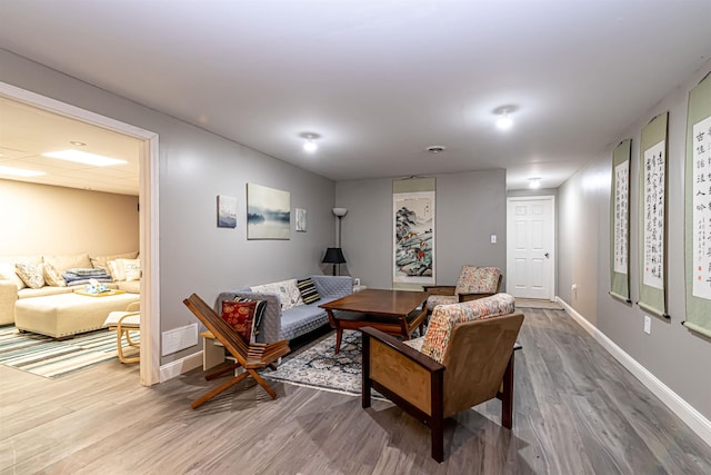 living room with baseboards, visible vents, and wood finished floors