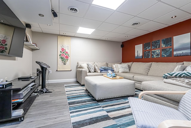 living area featuring baseboards, a drop ceiling, wood finished floors, and visible vents