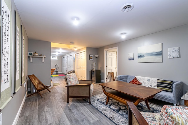 living room featuring visible vents, baseboards, and wood finished floors