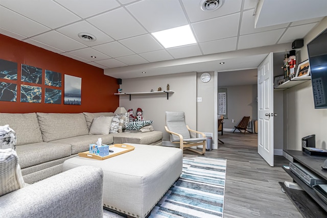 living area featuring visible vents, light wood-type flooring, and a paneled ceiling