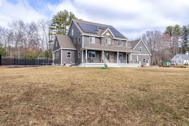 craftsman-style home featuring a porch, a shingled roof, a front lawn, and solar panels