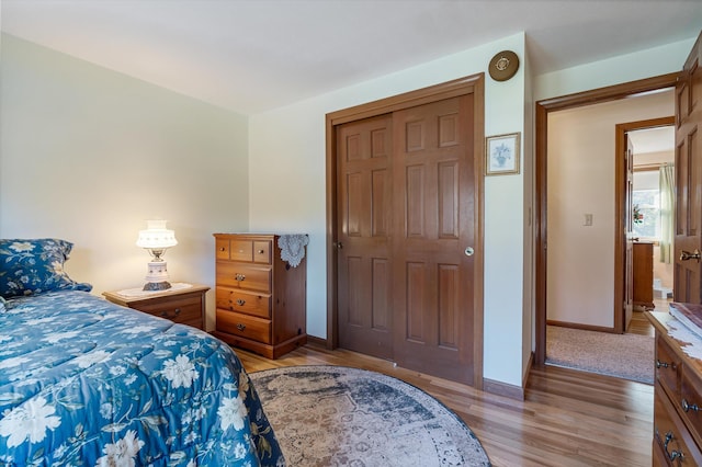 bedroom with baseboards, light wood finished floors, and a closet