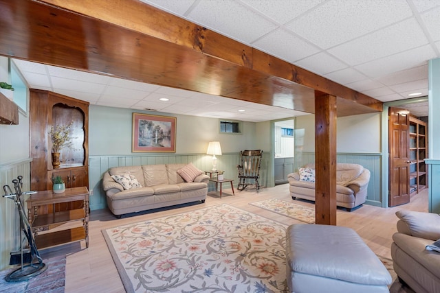 living room featuring wood finished floors, a drop ceiling, and a wainscoted wall