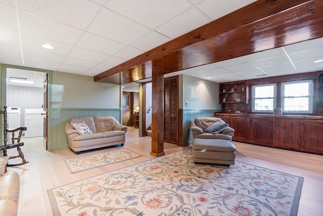 living room featuring washer and dryer, wainscoting, wood finished floors, and a paneled ceiling