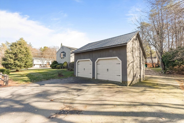view of side of home featuring metal roof, a yard, an outbuilding, and a detached garage