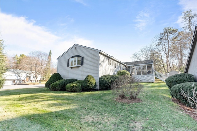view of side of property featuring a lawn and a sunroom