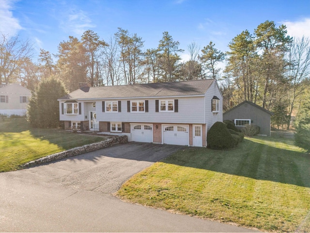 bi-level home featuring a garage, a front yard, and aphalt driveway