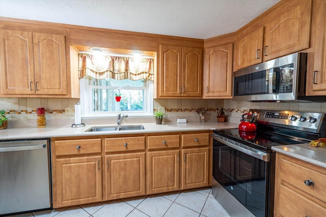 kitchen featuring backsplash, appliances with stainless steel finishes, a sink, and light countertops