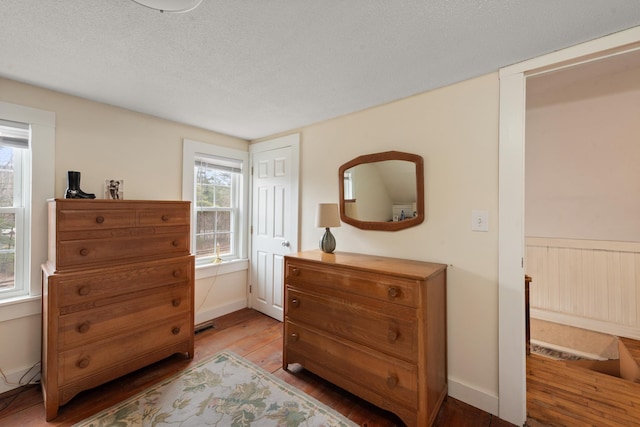 bedroom featuring baseboards, light wood finished floors, and a textured ceiling