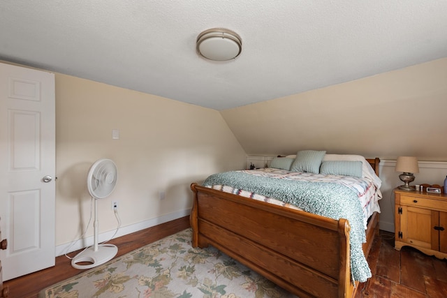 bedroom featuring baseboards, lofted ceiling, and wood finished floors