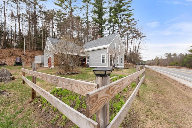 exterior space featuring a lawn, fence, and a shingled roof
