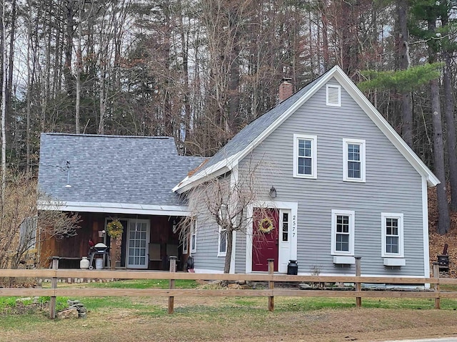 view of front of house featuring fence, a chimney, and a shingled roof
