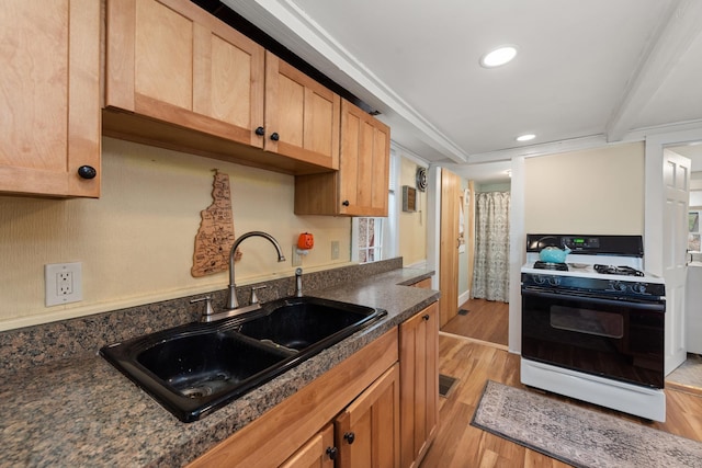 kitchen with a sink, recessed lighting, range with gas cooktop, and light wood finished floors