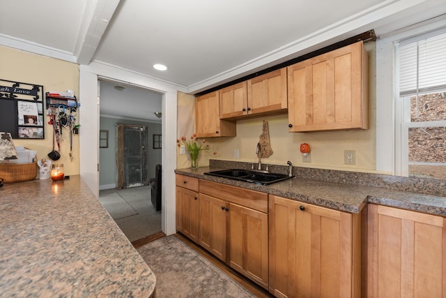 kitchen featuring light brown cabinets, dark countertops, baseboards, recessed lighting, and a sink