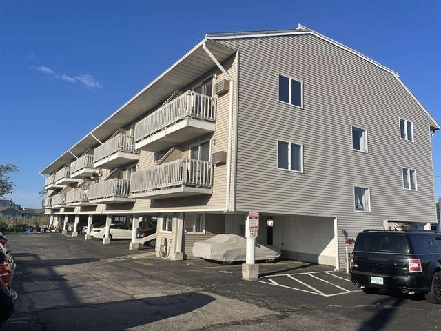 view of property with covered parking and a wall mounted AC