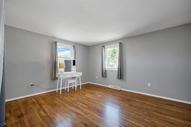 spare room featuring baseboards, visible vents, and wood finished floors