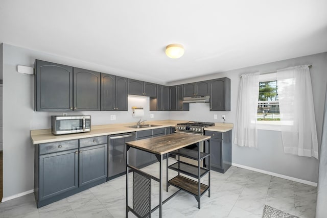 kitchen with stainless steel appliances, a sink, light countertops, marble finish floor, and under cabinet range hood